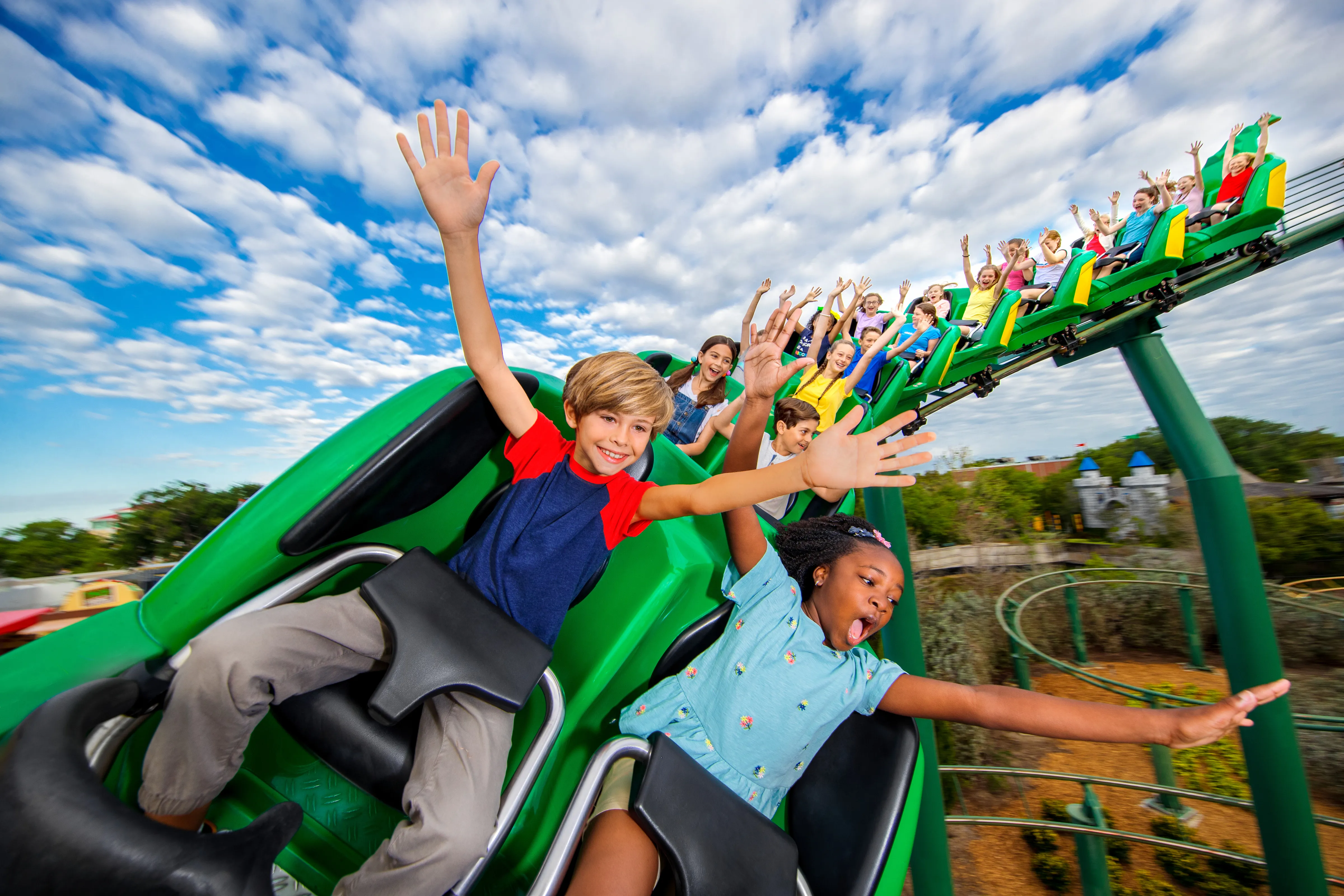 Children riding the Dragon Coaster with hands in the air