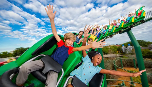 Children riding the Dragon Coaster with hands in the air