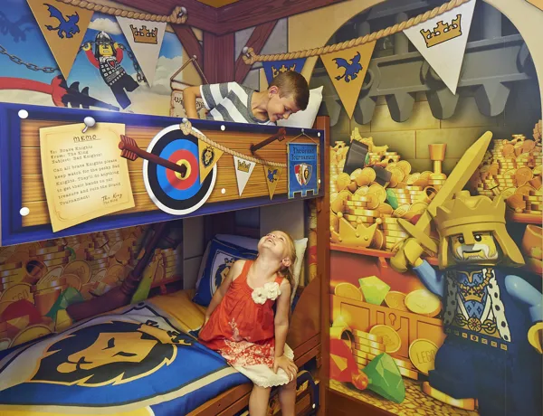 Children smiling at each other on bunk beds in a Knight's room in the LEGOLAND Castle Hotel