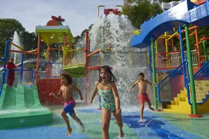 Children running from big water splash at Drench Towers