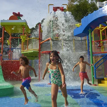 Children running from big water splash at Drench Towers