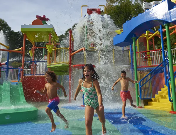 Children running from big water splash at Drench Towers
