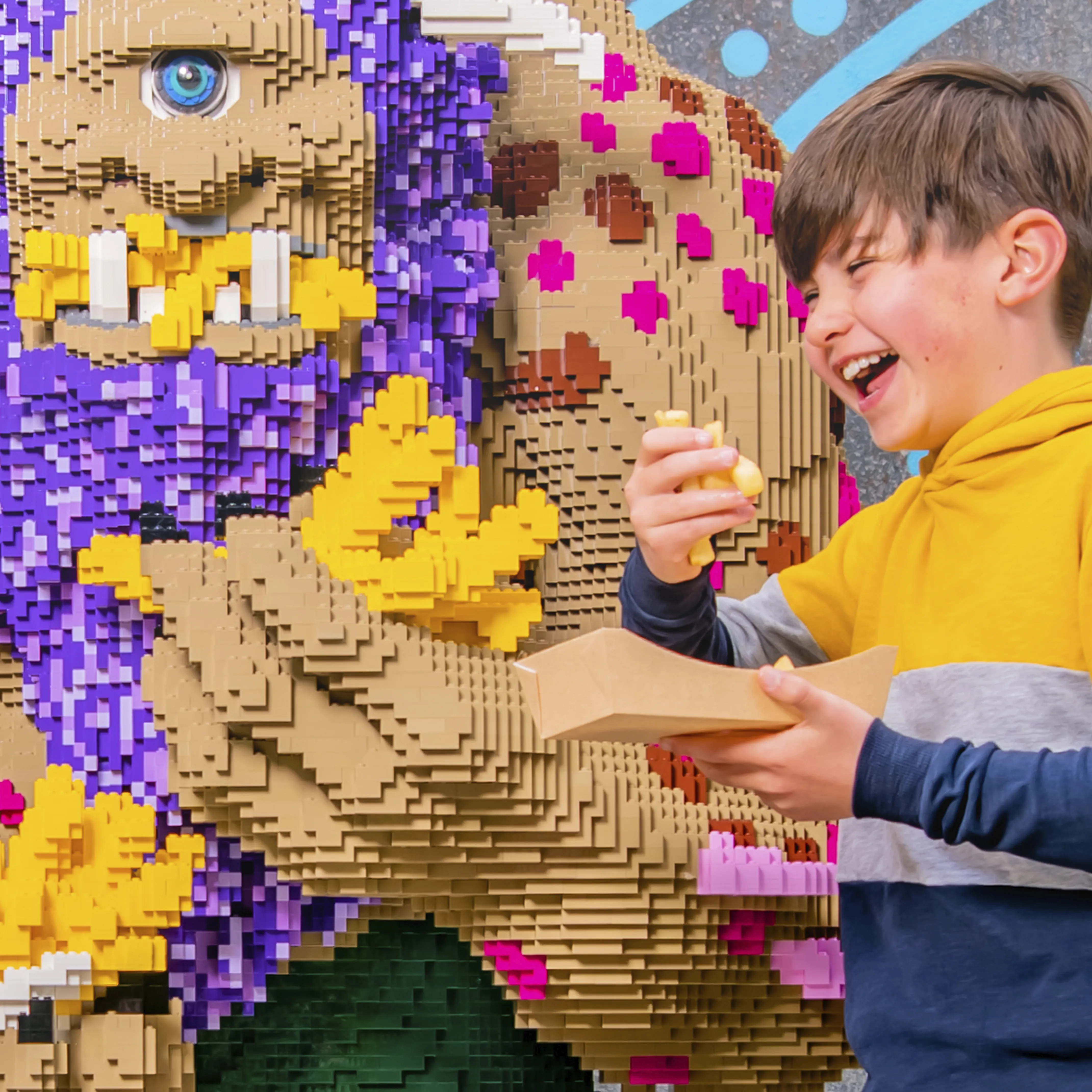 Boy eating chips next to a LEGO model of a troll outside The Hungry Troll restaurant